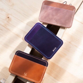 Three leather card wallets on a desk.